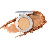 A single open compact of 100% Pure Fruit Pigmented® Eye Shadow 2g by 100% Pure in shimmery gold, with loose powder smeared around it on a white background.