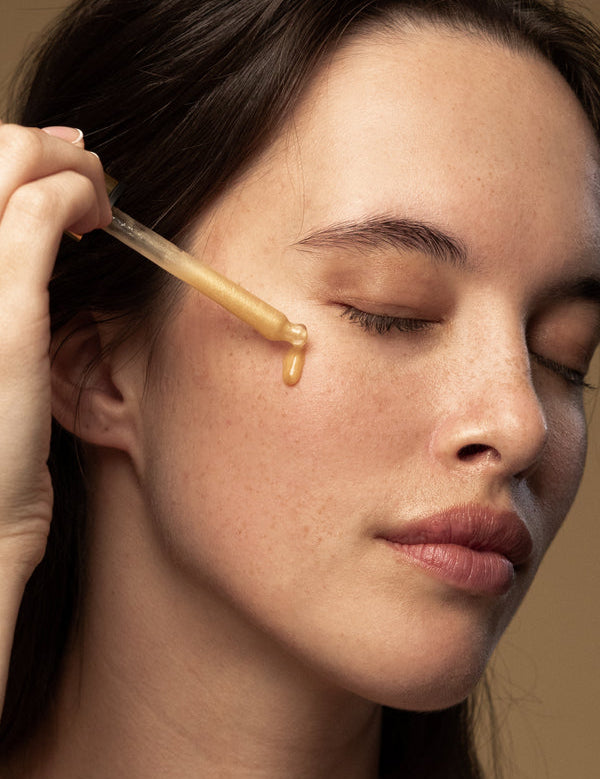 Model applying Antipodes Glow Vitamin C Brightening Serum with a dropper