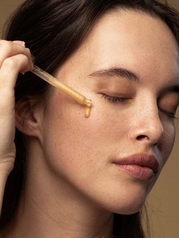 Model applying Antipodes Glow Vitamin C Brightening Serum with a dropper