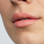 Close-up of lips in a matte, natural pink from Antipodes Moisture Boost Natural Lipsticks 4g. Skin looks smooth with freckles and light texture. "Golden Bay Nectar" at the bottom highlights long-lasting, natural color.