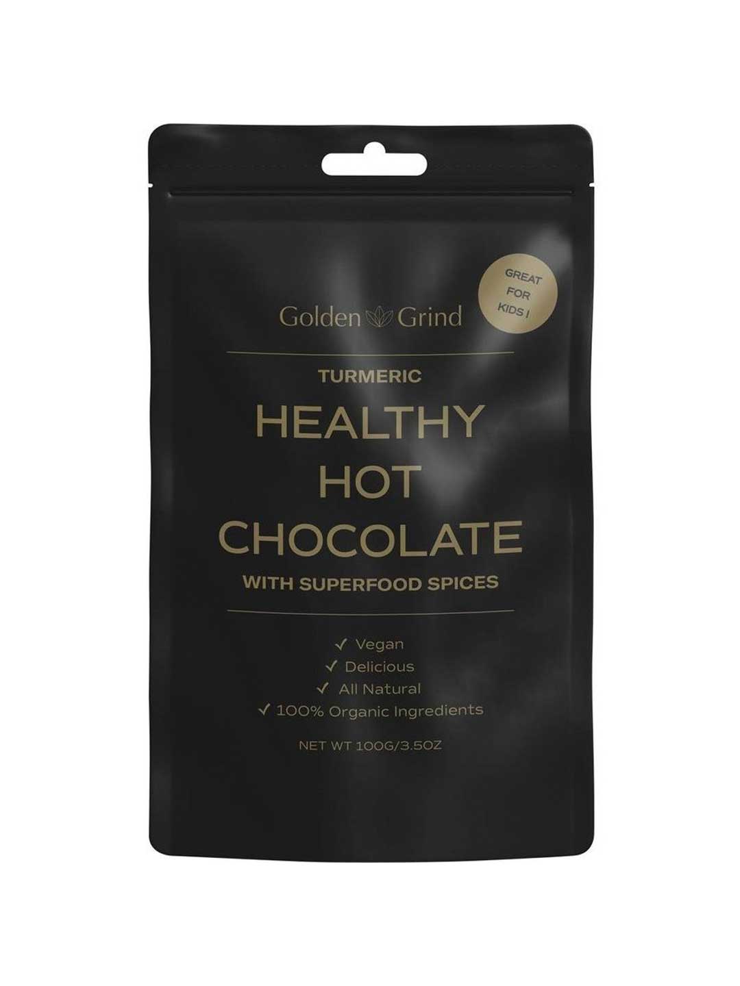 A black pouch labeled Golden Grind Turmeric Hot Chocolate Blend 100g—vegan, delicious, and all-natural with 100% organic ingredients including curcumin and Ceylon cinnamon. Superfood spices. Great for kids. Net weight: 100g.