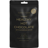 A black pouch labeled Golden Grind Turmeric Hot Chocolate Blend 100g—vegan, delicious, and all-natural with 100% organic ingredients including curcumin and Ceylon cinnamon. Superfood spices. Great for kids. Net weight: 100g.
