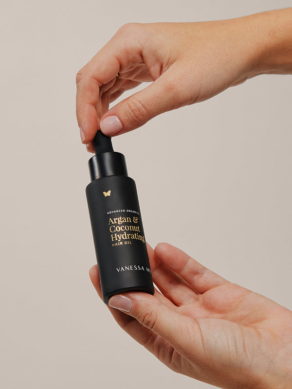 Vanessa Megan Argan and Coconut Hydrating Hair Oil bottle in hand