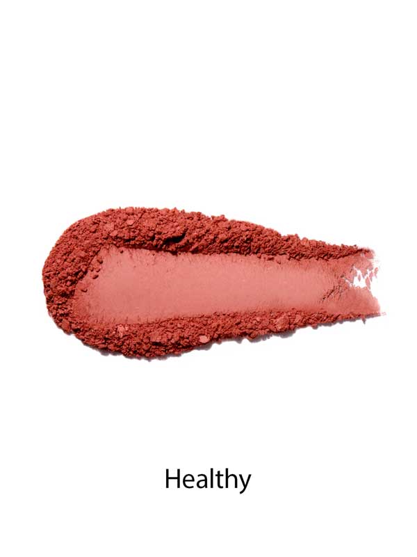 A swatch of 100% Pure Rice Powder Pressed Blush 9g in matte, dusty pink on a white background with "Healthy" below, demonstrating a natural flush and buildable coverage.