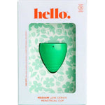 A green Hello Low Cervix Period Cup is shown in white packaging with floral patterns and orange "hello" text. The box highlights it as a Medium Low Cervix Menstrual Cup and notes its hypoallergenic material.
