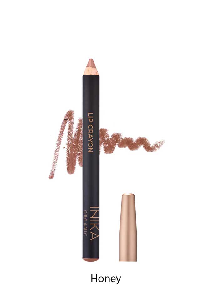 A brown INIKA Organic Lip Crayon 6.7g with gold labeling is displayed with its cap removed and a swatch behind it; the shade "Honey" is shown below, emphasizing this long-lasting lip liner’s natural, organic appeal.