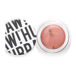 Hurraw! Copper Aura Balm 5.8g is a vegan, shimmery rose-gold cream highlighter in a round container. The white lid, featuring bold black text in a playful, overlapping style, is off and placed to the left of the open balm.
