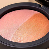 A close-up of the INIKA Organic Mineral Baked Blush Duo - Burnt Peach 6.5g compact, featuring two shimmery blush shades—light pink and burnt peach—divided diagonally in a sleek black vegan case.