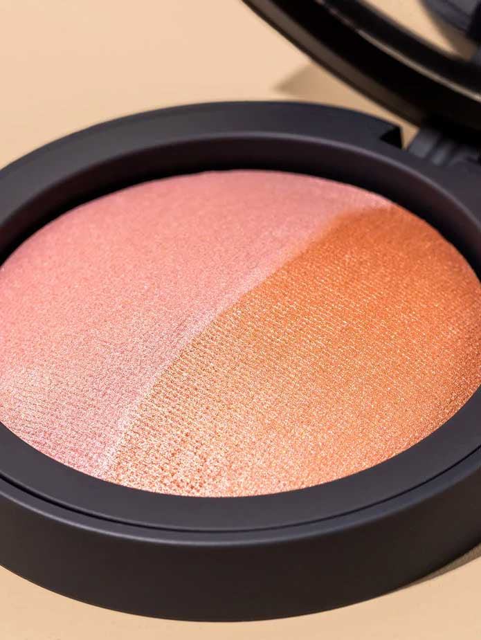 A close-up of the INIKA Organic Mineral Baked Blush Duo - Burnt Peach 6.5g compact, featuring two shimmery blush shades—light pink and burnt peach—divided diagonally in a sleek black vegan case.