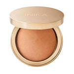 A gold compact of INIKA Organic Baked Mineral Bronzer - Sunkissed 9g with the lid partially open, revealing the warm brown vegan bronzer inside for a natural, sun-kissed glow.