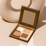 The INIKA Organic Brow Palette 8g, an open vegan palette with four neutral shades and a mirror, is shown on a beige surface next to a round, textured decor object—ideal for creating versatile brow looks.