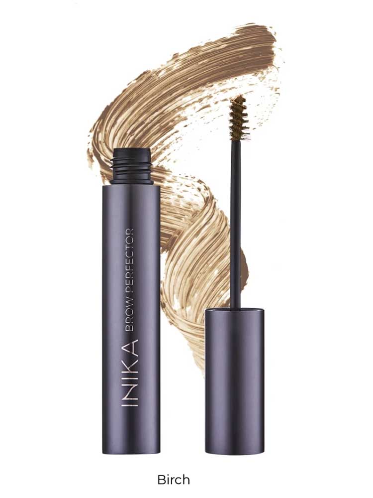 A tube of INIKA Organic Brow Perfector 6.5ml with its wand applicator removed sits in front of a light brown swatch. The shade name "Birch" is displayed below the image.
