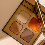 The INIKA Organic Eyeshadow Quad - Sunset 8g features four talc-free shades—gold, orange, bronze, and brown—in a gold mirrored case. Photographed on a light beige surface.