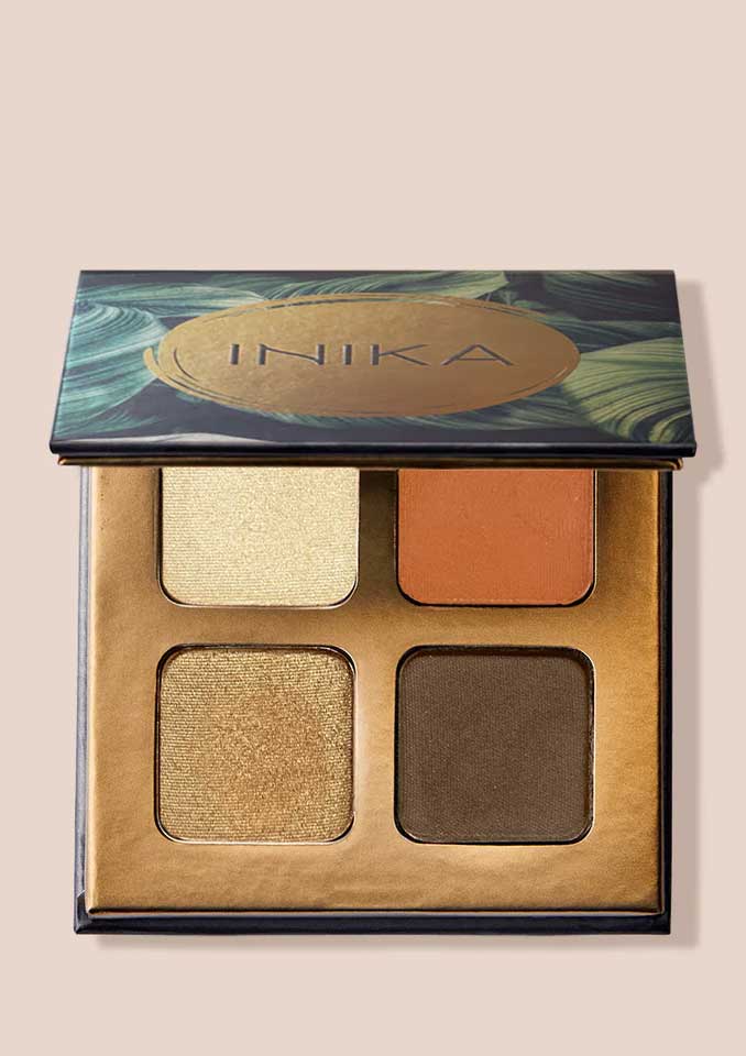 An open INIKA Organic Eyeshadow Quad - Sunset 8g shows four shades—shimmery gold, matte orange, shimmery bronze, and matte brown—in a decorative case with a green and gold lid design.