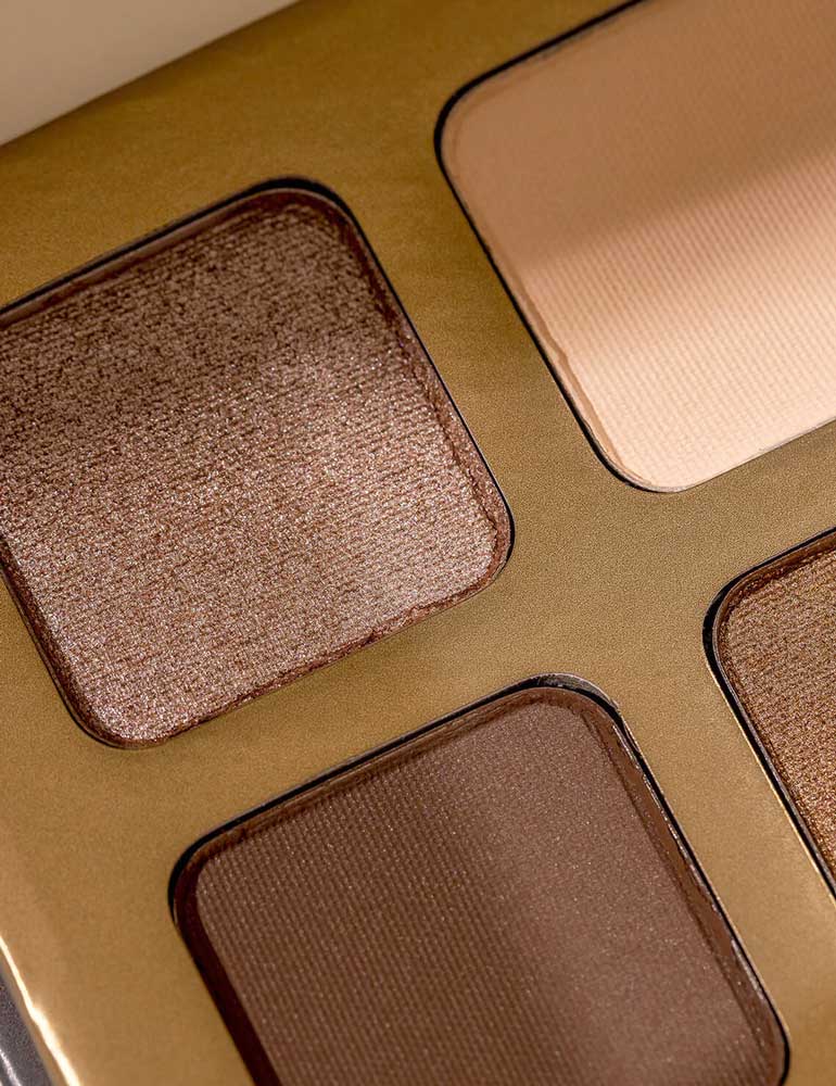 Close-up of INIKA Organic Eyeshadow Quad - Wind 8g, showing four talc-free shades—shimmering bronze, matte beige, matte brown, and shimmering gold—in square pans set in a sleek metallic gold case.