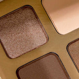 Close-up of INIKA Organic Eyeshadow Quad - Wind 8g, showing four talc-free shades—shimmering bronze, matte beige, matte brown, and shimmering gold—in square pans set in a sleek metallic gold case.