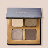 The INIKA Organic Eyeshadow Quad - Wind 8g is a vegan, talc-free palette in a black and gold case, featuring four neutral shades—beige, taupe, shimmery champagne, and matte brown. The lid displays "INIKA" in gold lettering.