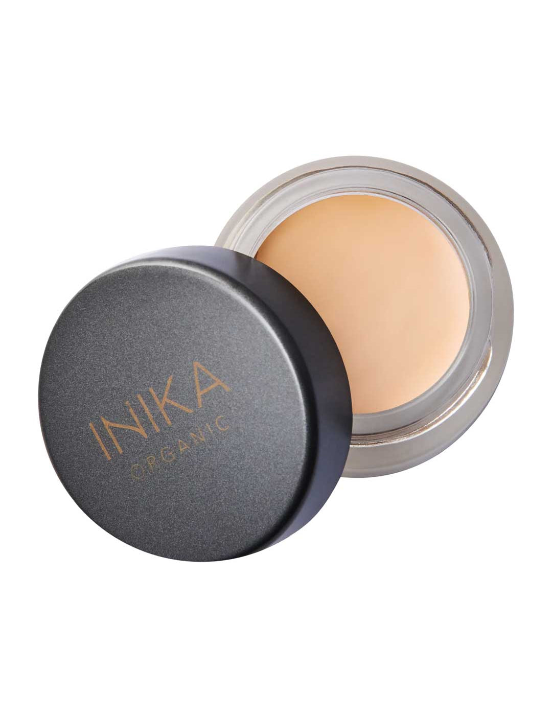 An open container of INIKA Organic Full Coverage Concealer 3.5g with a black lid beside it, showing the beige cream inside.