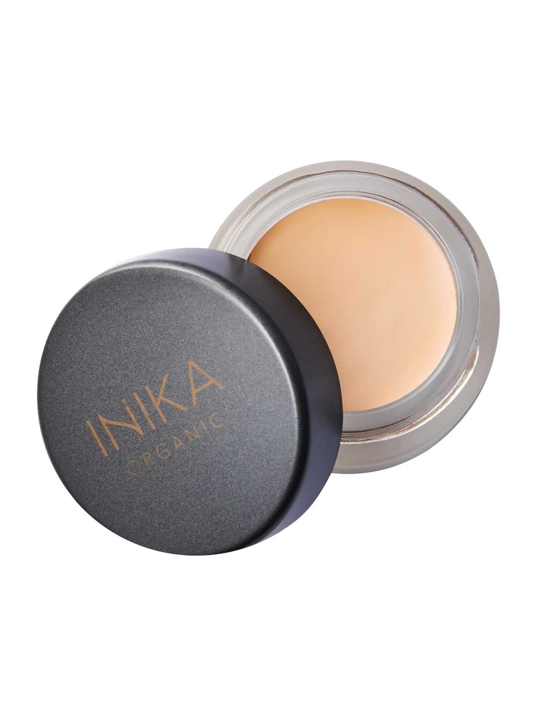 An open container of INIKA Organic Full Coverage Concealer 3.5g with a black lid beside it, showing the beige cream inside.