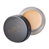 An open container of INIKA Organic Full Coverage Concealer 3.5g with a black lid beside it, showing the beige cream inside.