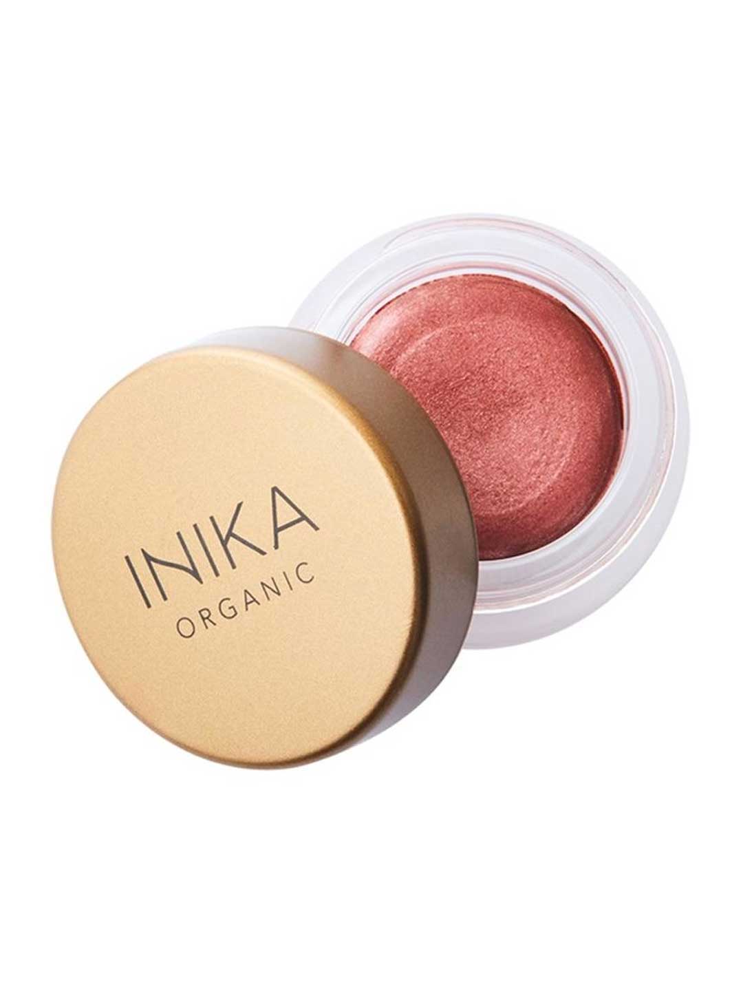 A small round jar of INIKA Organic Lip & Cheek Cream Petals 3.5g with a gold lid, slightly open to show shimmery pink cream inside.