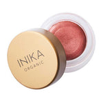 A small round jar of INIKA Organic Lip & Cheek Cream Petals 3.5g with a gold lid, slightly open to show shimmery pink cream inside.