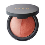 A round compact with a partially open black lid shows the INIKA name in gold. Inside is the INIKA Organic Mineral Baked Blush Duo - Burnt Peach 6.5g, a vegan blush featuring dome-shaped peach and bronze shades.