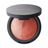 A round compact with a partially open black lid shows the INIKA name in gold. Inside is the INIKA Organic Mineral Baked Blush Duo - Burnt Peach 6.5g, a vegan blush featuring dome-shaped peach and bronze shades.