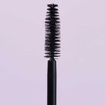 A close-up of the INIKA Organic Purity Lash Mascara - Black 8.5ml wand with bristles, standing upright against a light purple background—ideal for sensitive eyes and hypoallergenic needs.
