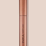 The INIKA Organic Purity Lash Mascara - Black 8.5ml stands upright in its metallic rose gold tube against a light beige background, with the brand and product name printed vertically—ideal for sensitive eyes.