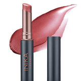 A tube of INIKA Organic Tinted Lip Balm - Rose 3.5g with the cap off reveals a rosy pink shade, while a background swipe highlights its creamy texture and subtle shimmer.
