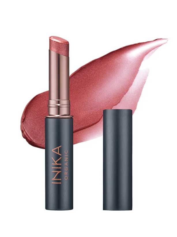 A tube of INIKA Organic Tinted Lip Balm - Rose 3.5g with the cap off reveals a rosy pink shade, while a background swipe highlights its creamy texture and subtle shimmer.
