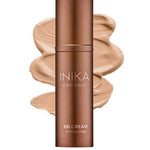 A bronze bottle of INIKA Organic Organic BB Cream 30ml in shade Beige stands before a beige cream smear labeled "Beige"—an organic BB cream that provides a natural satin finish.