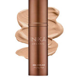 A bronze bottle of INIKA Organic Organic BB Cream 30ml in shade Beige stands before a beige cream smear labeled "Beige"—an organic BB cream that provides a natural satin finish.