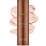 A bronze bottle of INIKA Organic Organic BB Cream 30ml in Porcelain stands before a light beige cream smear, highlighting its natural satin finish. This vegan beauty balm offers flawless coverage with a radiant glow.