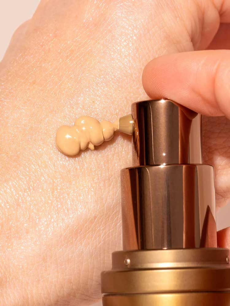 A close-up shows a hand dispensing INIKA Organic BB Cream 30ml from a bronze pump bottle onto the skin, offering a natural satin finish.