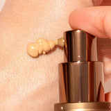 A close-up shows a hand dispensing INIKA Organic BB Cream 30ml from a bronze pump bottle onto the skin, offering a natural satin finish.