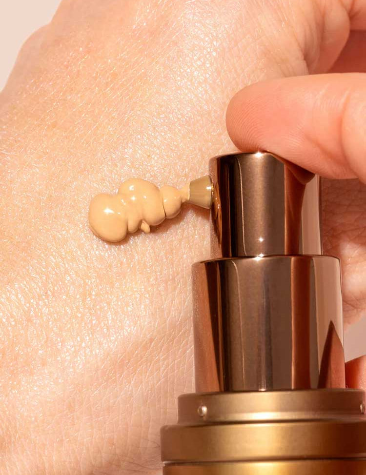 A close-up shows a hand dispensing INIKA Organic BB Cream 30ml from a bronze pump bottle onto the skin, offering a natural satin finish.