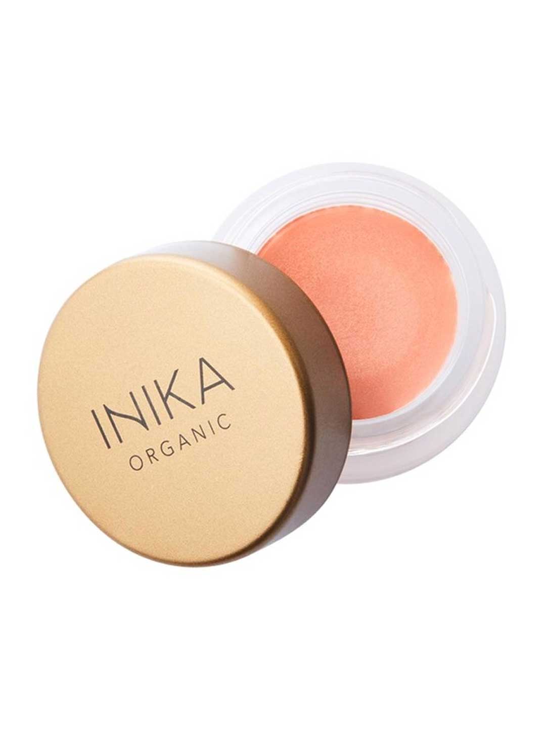 The INIKA Organic Lip & Cheek Cream Morning 3.5g is a small round vegan makeup container with a gold lid, partly open to show its natural peach blush shade.