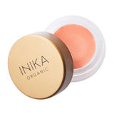 The INIKA Organic Lip & Cheek Cream Morning 3.5g is a small round vegan makeup container with a gold lid, partly open to show its natural peach blush shade.