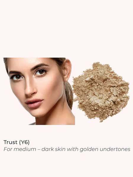 A woman with medium skin and golden undertones sits beside INIKA Organic Loose Mineral Foundation SPF25 8g. Text: Trust (Y6) for medium–dark skin with golden undertones.