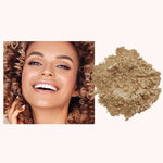 A smiling woman with curly hair is pictured next to a pile of INIKA Organic Loose Mineral Foundation SPF25 8g against a light background.