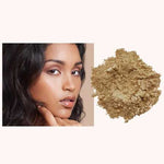 A woman with smooth, glowing skin touches her chin beside a pile of INIKA Organic Loose Mineral Foundation SPF25 8g on a light background.
