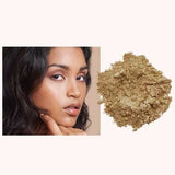 A woman with smooth, glowing skin touches her chin beside a pile of INIKA Organic Loose Mineral Foundation SPF25 8g on a light background.