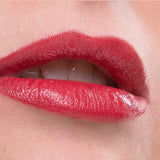 A close-up of lips wearing Benecos Natural Lipsticks 4.5g in glossy red, slightly parted to reveal white teeth. The background is soft pink with "Just Red" text at the bottom.