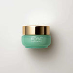 A small, round, light green jar with a shiny gold lid labeled “KORA Organics Active Algae Lightweight Moisturiser” rests on a white background—ideal for those with oily or combination skin seeking lightweight hydration.