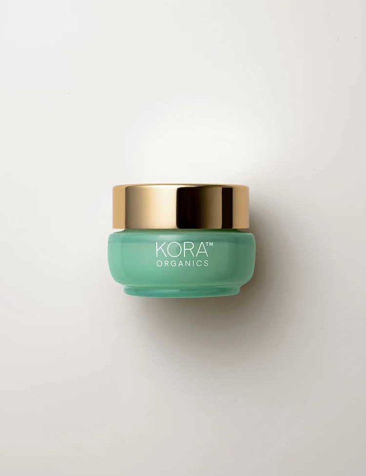 A small, round, light green jar with a shiny gold lid labeled “KORA Organics Active Algae Lightweight Moisturiser” rests on a white background—ideal for those with oily or combination skin seeking lightweight hydration.