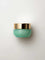 A small, round, light green jar with a shiny gold lid labeled “KORA Organics Active Algae Lightweight Moisturiser” rests on a white background—ideal for those with oily or combination skin seeking lightweight hydration.