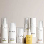 Seven white and yellow bottles and jars of LAMAV Age-Defence Complete Skincare Collection for Oily/Combination Skin (7 pack) are arranged in two rows on a light surface, set against a plain beige background.