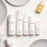 A flat lay of LAMAV Age-Defence Complete Skincare Collection for Oily/Combination Skin (7 pack) arranged on white plates—bio-active cleansers, fluid, serum, cream, and oil dropper—ideal for oily and combination skin.